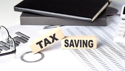 Wall Mural - TAX SAVING - text on a wooden block with chart and notebook