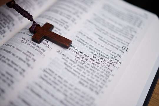 Background, christian and rosary on bible book for praying, spiritual faith or holy worship to God in heaven. Closeup of cross for studying religion, reading prayer or scripture story of Jesus Christ