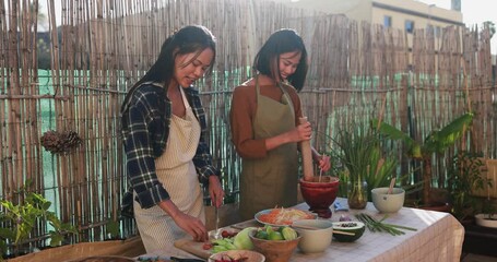 Wall Mural - Happy asian family preparing papaya salad with fresh spicy dressing at home patio outdoor - Sisters cooking dinner together 