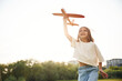 Happy little girl is playing with toy plane outdoors