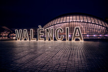 Illumianted Valencia Neon Sign In Front Of The Hemisferic Building Of The City Of Arts And Sciences.