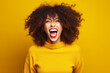 Woman with curly hair and yellow sweater is making funny face.