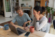 © ReeldealHD images - Happy lesbian couple at home looking at personal finances using a laptop and smartphone
