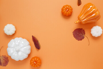 Wall Mural - Set of ceramic pumpkins and candles on orange background. Fall decor, interior decoration. Flat lay, top view, copy space