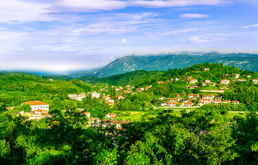 Wall Mural - travel summer view from hill to a nice european town with amazing buildings, green hills and mountains with amazing cloudy evening sky on background