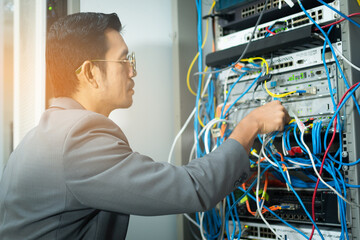 it technician checking the network connection in server room for maintenance