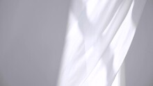 White Transparent Fabric Flutters In The Wind. Long White Curtains In A Bright Studio. Sheer White Curtains Blowing In The Wind. Slow Motion. Footage
