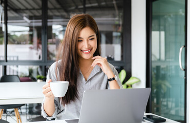 Wall Mural - Cheerful business lady working on laptop in office, Asian happy beautiful businesswoman wearing shirt work in workplace. Attractive female employee office worker smile.