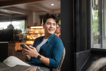 Young Asian man using smart phone in cafe
