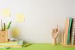 © ActionGP - Creative inspiration scene. Side view photo stationery-filled desk with pencils, pens, books holder, notepads, wooden mannequin hand, stapler, sticky notes on beige wall backdrop. Ad space available