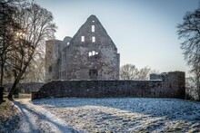 Idyllic Winter Scene Of Ruins Of An Ancient Castle Bathed In The Golden Glow Of The Setting Sun