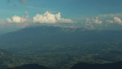 Poster - Landscape view of hazy green mountains with moving white clouds on the horizon