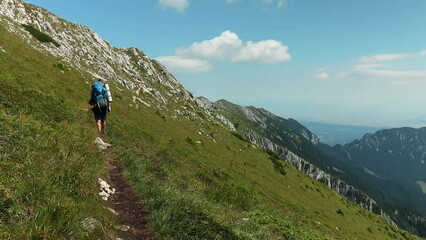 Sticker - Man hiking rocky peak of Piatra Craiului Mountains range under a blue sunny sky