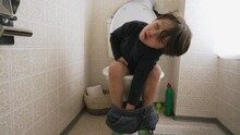 One Cute Little Boy Sitting On Toilet Seat. Child Doing His Hygiene Needs
