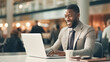 © BlazingDesigns - Handsome young businessman sitting office and working on laptop computer. Smiling black man using laptop. Professional african american CEO managing investment strategy. Portrait of top manager.
