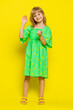 © Andrii Iemelianenko - Young blonde school girl smiling friendly at camera and waving hands gesturing hello or goodbye, welcoming with hospitable expression. Preteen female child kid isolated on yellow background. Vertical