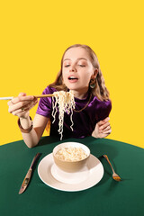 Wall Mural - Young woman eating Chinese noodles at table on yellow background