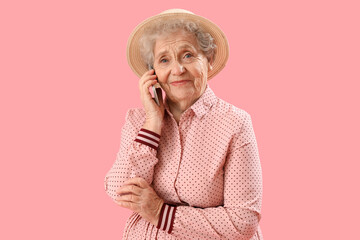 Poster - Senior woman talking by mobile phone on pink background