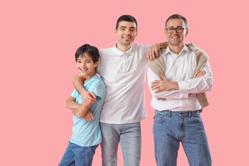 Wall Mural - Happy little boy with his dad and grandfather on pink background