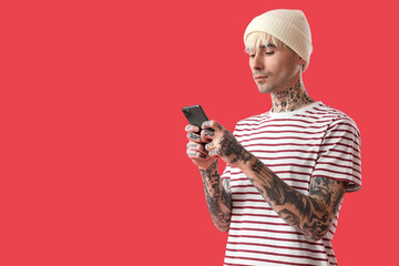 Poster - Tattooed young man using mobile phone on red background