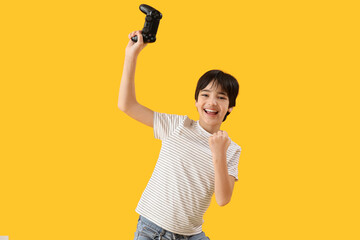 Wall Mural - Happy little boy with game pad on yellow background