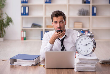 Wall Mural - Young male employee in time management concept