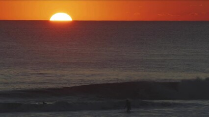 Wall Mural - beautiful evening sunset with big sun in the atlantic ocean at portugal coast. surfers ride the wave