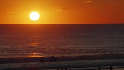 Wall Mural - beautiful evening sunset with big sun in the atlantic ocean at portugal coast. surfers ride the wave