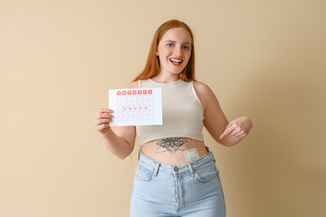 Wall Mural - Young woman with menstrual calendar pointing at applied contraceptive patch on beige background