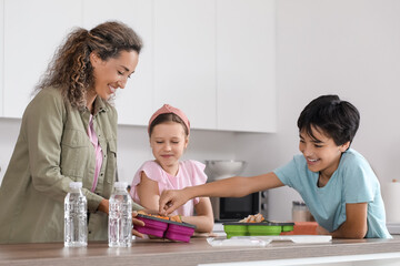 mother with her little children and school lunchboxes in kitchen