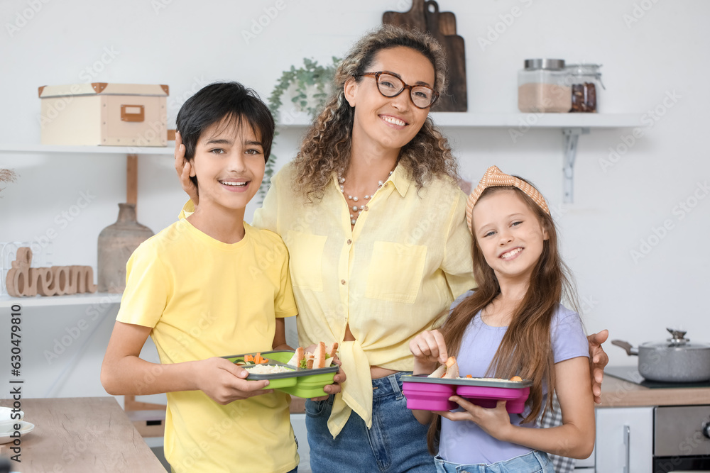 Mother with her little children and school lunchboxes in kitchen