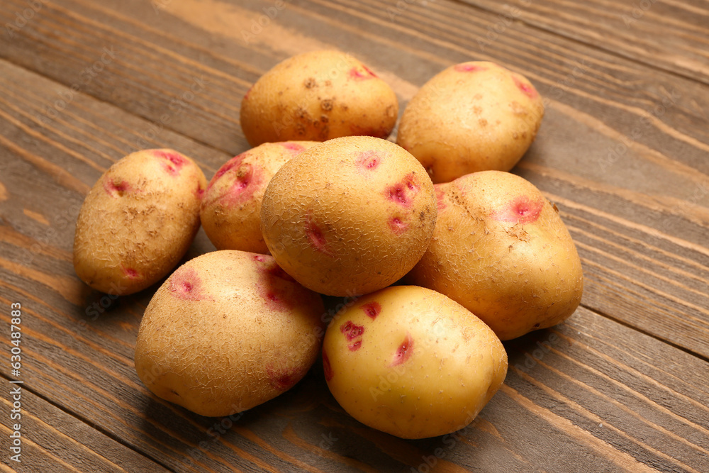 Heap of fresh raw potatoes on wooden background