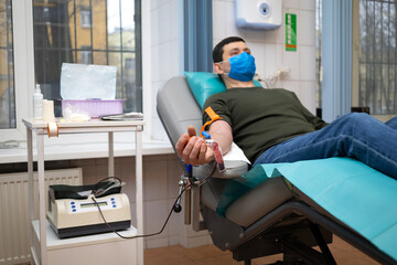 Wall Mural - man donor for bone marrow donation blood in laboratory. male hand holding red ball, prevention of diseases, illness hemodialysis transfusion in hospital. soft focus