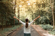 © kieferpix - Young woman in autumn forest raising arms, expressing carefree happiness and connection with nature.