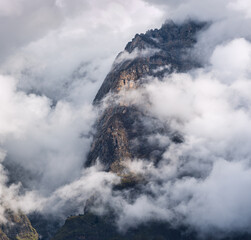 Wall Mural - mountain peak in low clouds at sunset in nepal. dramatic landscape with beautiful high rocks in fog,