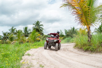 Poster - Happy young couple in nature on a quad bike. Young man enjoying a quad bike ride in countryside. Man driving and woman enjoying the ride with her hands raised on a summer day.