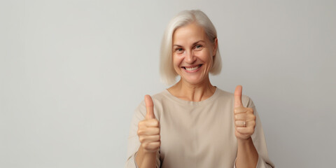 Happy woman giving thumbs up on a solid background