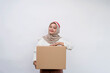 Cheerful Asian muslim woman celebrating indonesian independence day carrying package box isolated on white background. Indonesian independence day on 17 august concept