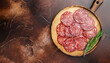 Meat food sausage salami slices on cutting board on aged brown background, mockup. Copy space, flat lay top view
