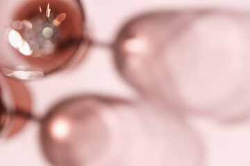 Wall Mural - wine glasses defocused, rose wine blurred on pink background with light flare, optical blur, bokeh. 