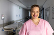 © wavebreak3 - Portrait of happy caucasian female doctor wearing scrubs in corridor at hospital, copy space