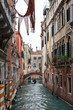 Narrow streets and canals of old Venice with boats and gondoliers on a cloudy spring day