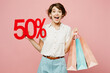 © ViDi Studio - Young surprised shocked woman wear casual clothes hold shopping paper package bags show 50 percent look camera scream isolated on plain pink color background studio. Black Friday sale buy day concept.