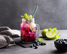 Refreshing Blueberry Mojito Or Lemonade With Lime, Mint And Ice On A Dark Background. Summer Healthy Non-alcoholic Drink Made From Fruits And Berries.