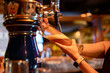 © pavel siamionov - bartender woman hand at beer tap pouring a draught beer in glass serving in a restaurant or pub
