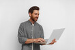 © Daria - Smiling male entrepreneur working on laptop while standing on white background
