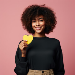 Canvas Print - Beautiful girl with curly hair holding a small yellow heart sticker