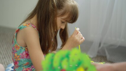 the girl sits and concentrates on tasks for development. it is necessary to sew small details to the