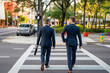 © Volodymyr - Two elegant businessmen walking outdoors together in the streets with office building. Business men walking outdoors together in the street discussing and chatting. Businessmen from work.
