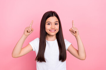 Photo portrait of pretty young child girl fingers point up empty space wear trendy white outfit isolated on pink color background